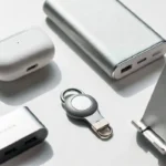 Flat lay of best small gadgets including earbuds, power bank, USB hub, and phone stand on white background