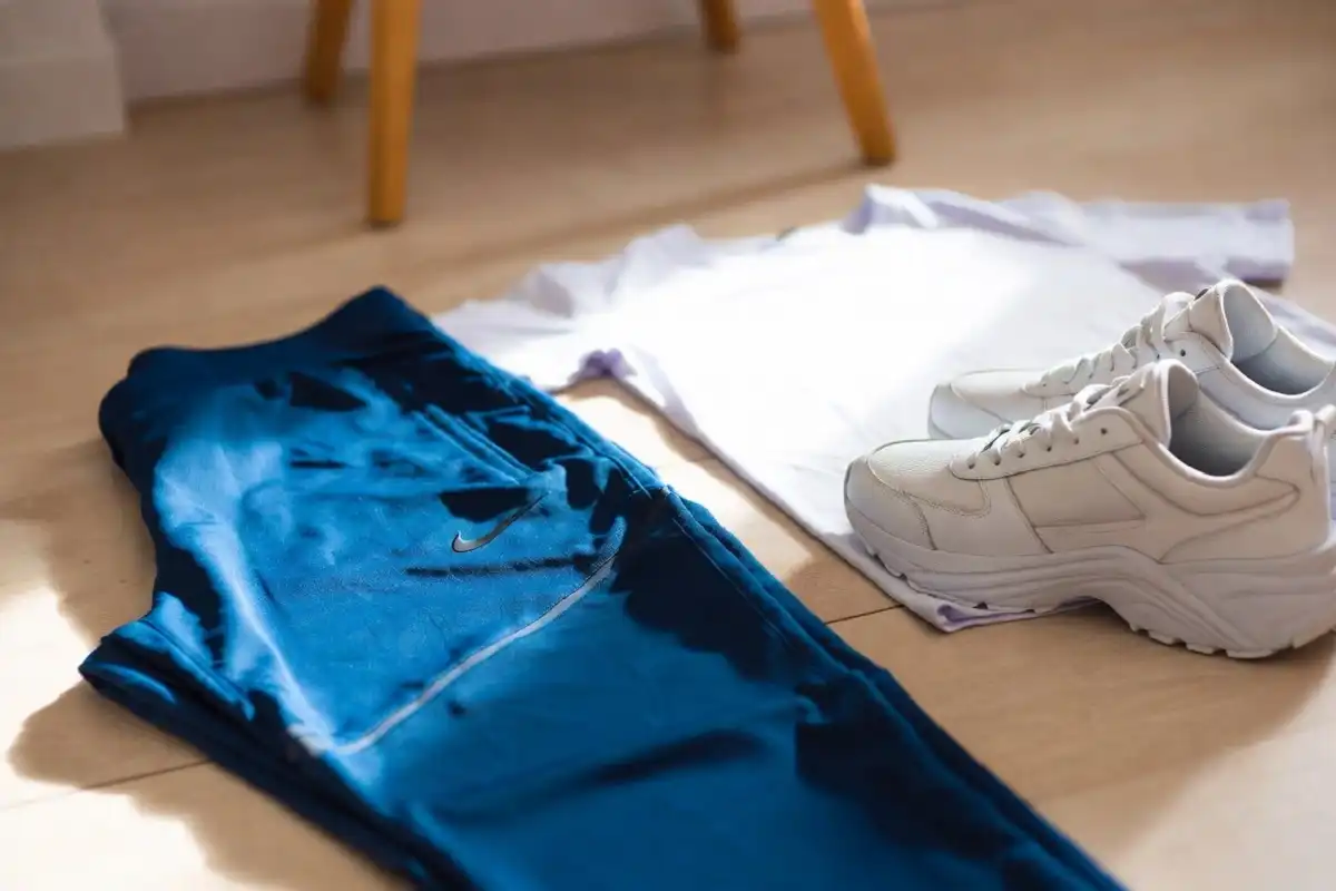 A styled outfit flat-lay featuring Nike Tech joggers in blue paired with white sneakers and a neutral top