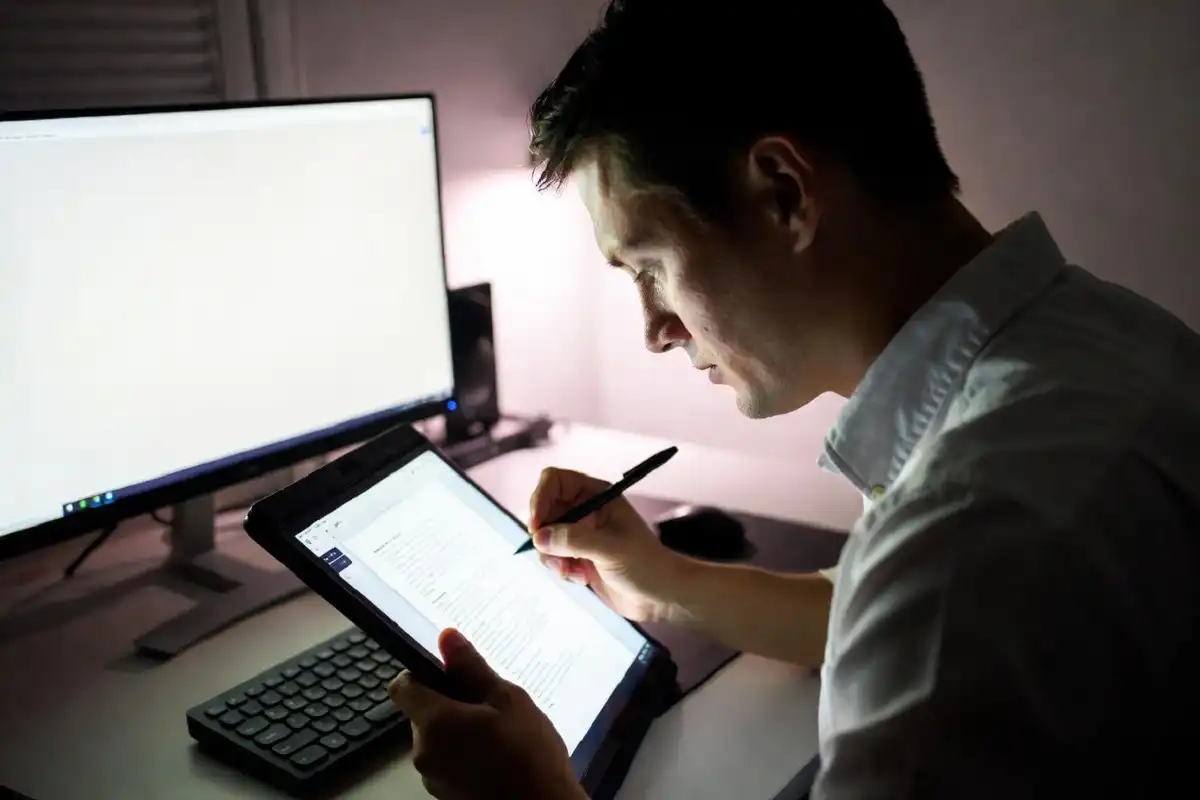 Professional using a digital paper tablet to annotate documents at a desk
