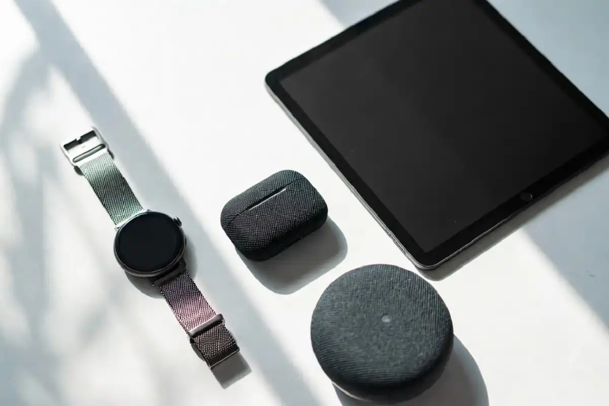 A curated flat lay of dream gadgets including a smartwatch, tablet, and wireless earbuds on a white desk