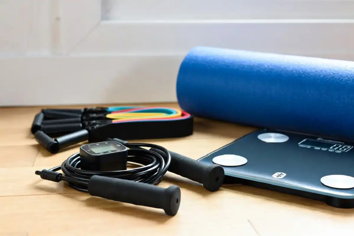 Home gym setup with smart fitness gadgets including a jump rope, foam roller, and resistance bands
