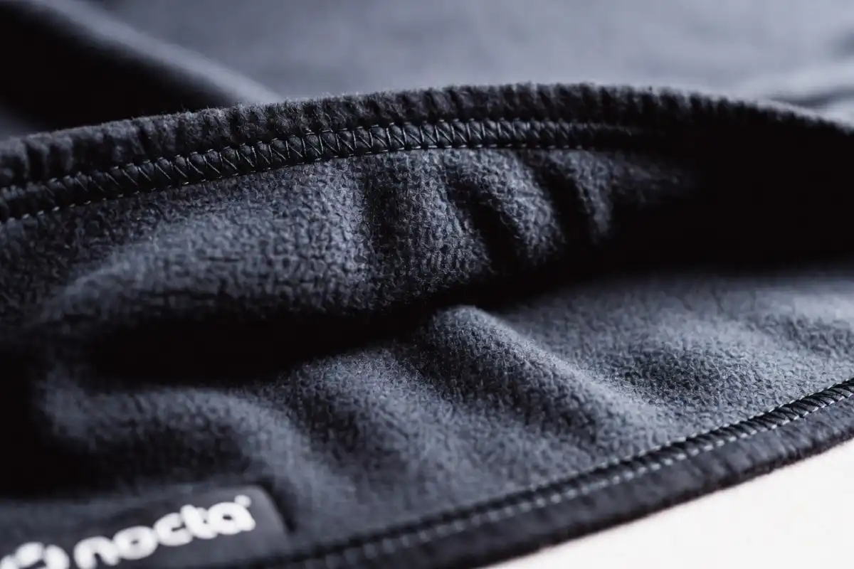 Close-up of nocta tech fleece bonded fabric texture and logo detail in studio lighting