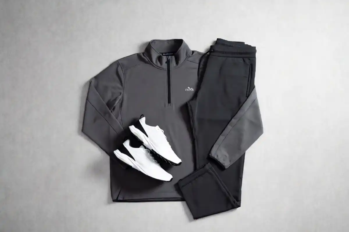 Nocta tech fleece styled with matching joggers and white sneakers in a flat-lay overhead shot