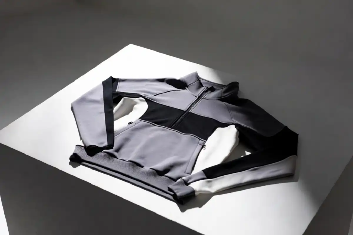Nocta tech fleece hoodie laid flat on a white surface in editorial product photography style