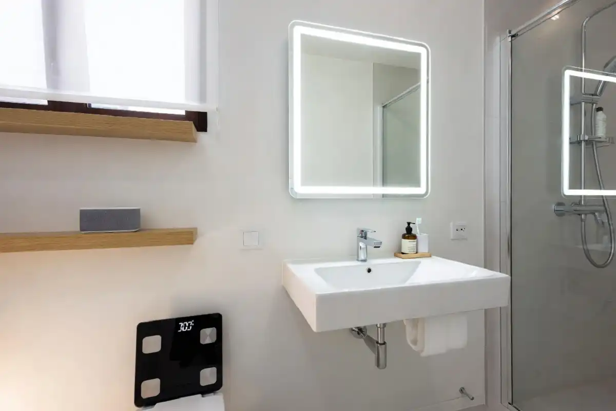 A well-organized modern bathroom with multiple smart gadgets including a digital scale, Bluetooth speaker, and smart mirror