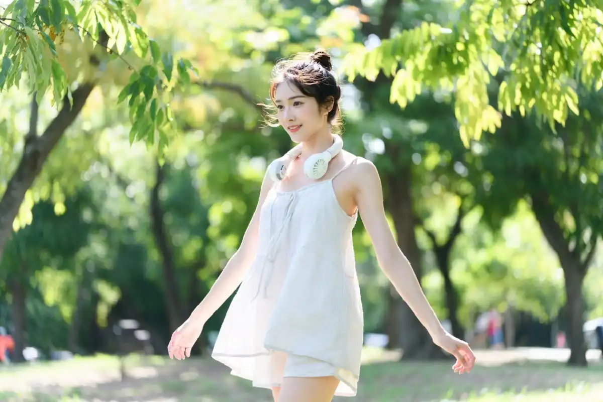 Woman wearing portable neck fan while walking outdoors in summer