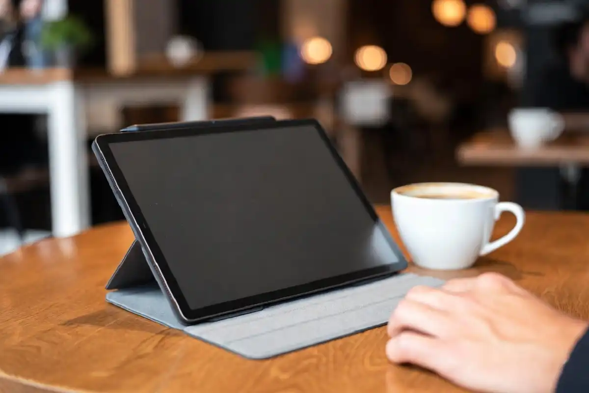 reMarkable 2 in a folio cover on a coffee shop table beside a coffee cup in warm ambient light