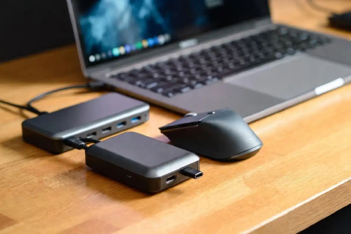 Small gadgets for work including portable charger, wireless mouse, and USB-C hub on a modern desk