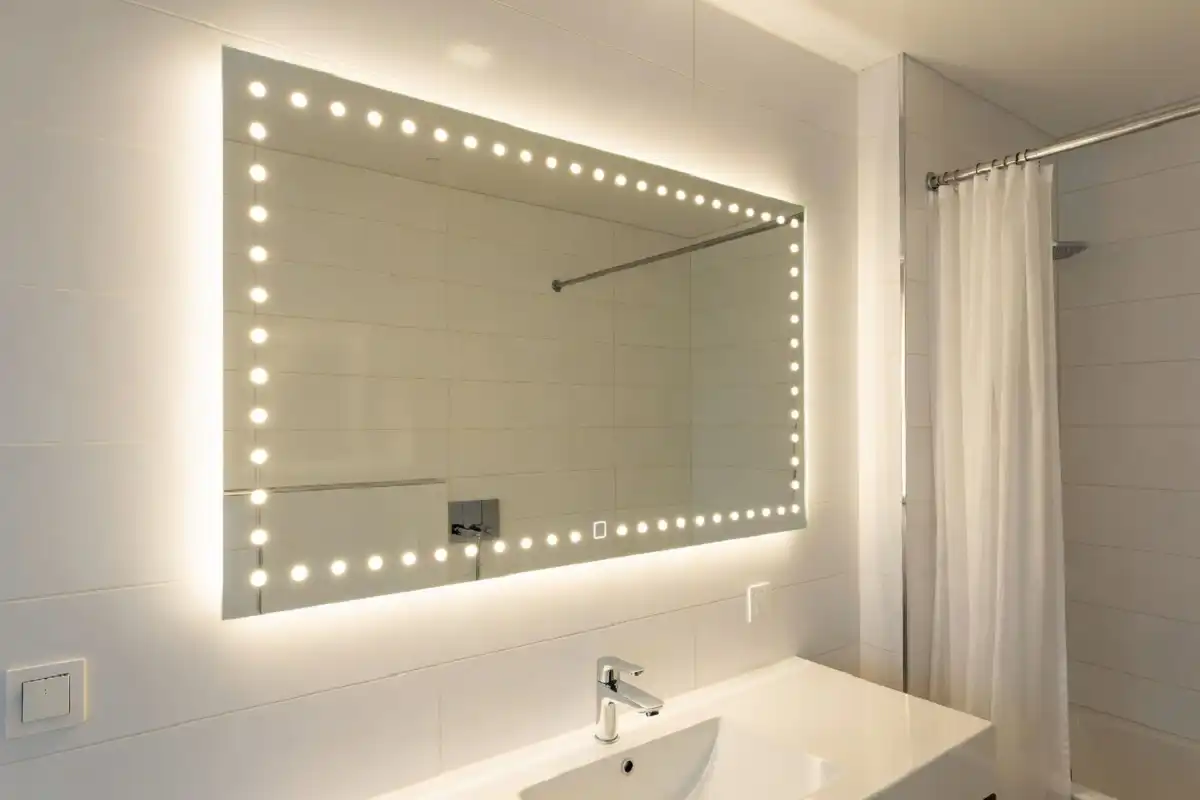 A smart LED bathroom mirror with touch controls mounted above a modern sink