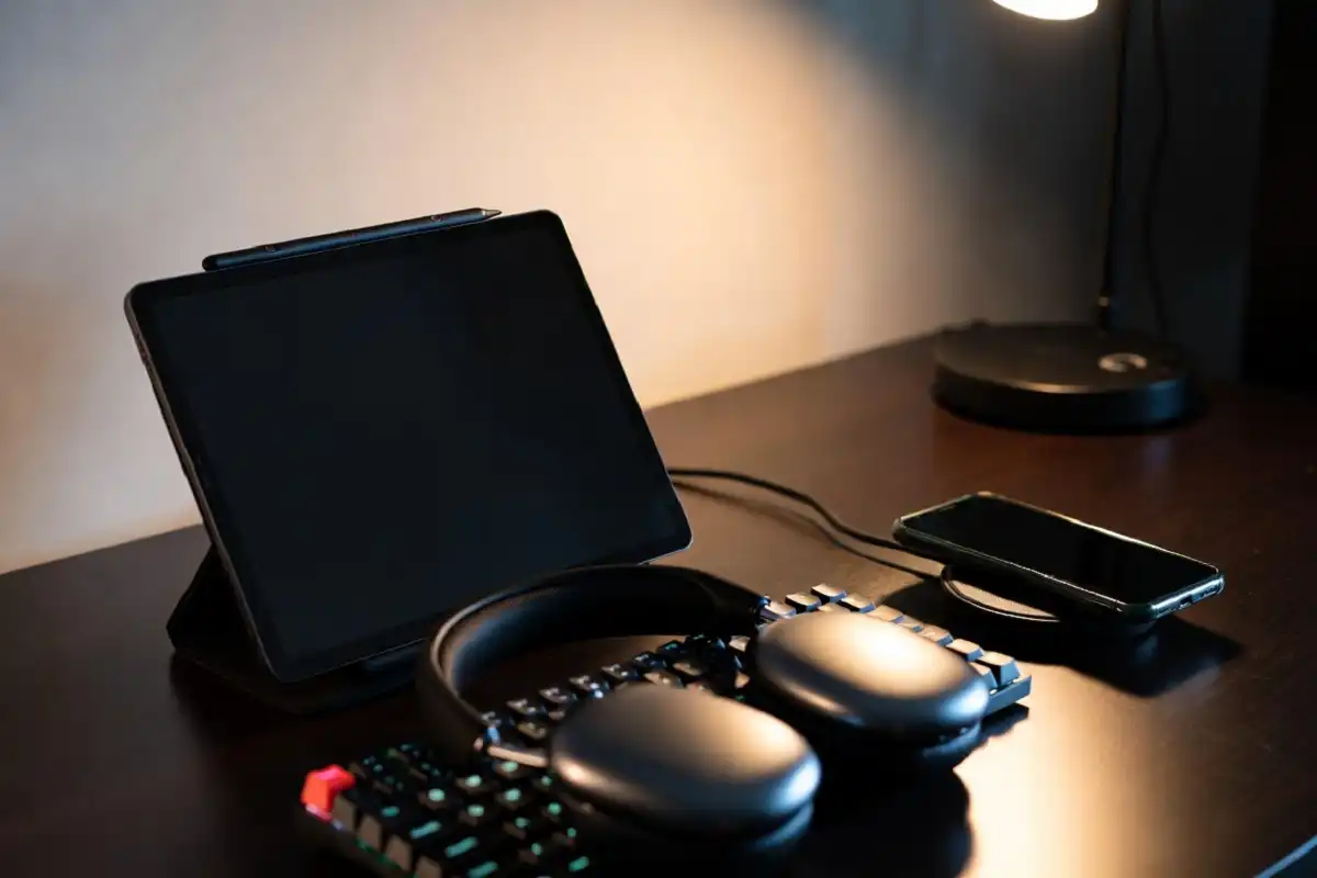 Smart gadgets for men at a clean workspace including an e-ink tablet, headphones, and a wireless charging pad