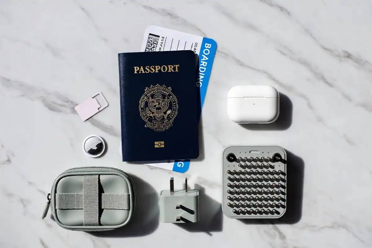 Best travel gadgets flat lay showing power bank earbuds adapter and tracker on a passport