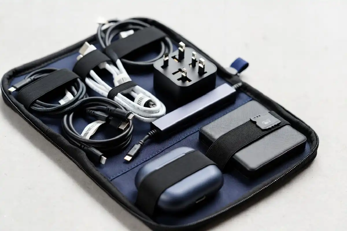 Travel gadgets organized in tech pouch with cables adapters and earbuds neatly arranged