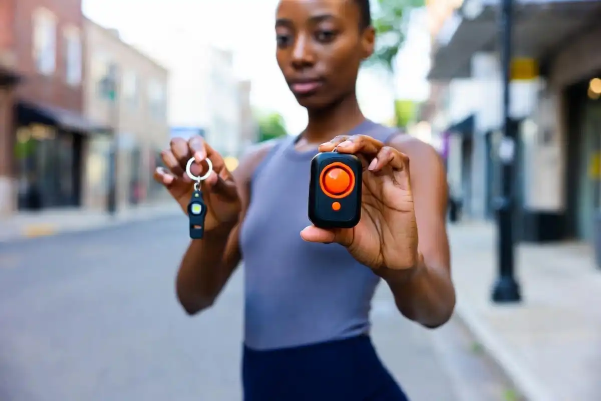 Women holding self defence safety gadgets including a personal alarm and safety keychain