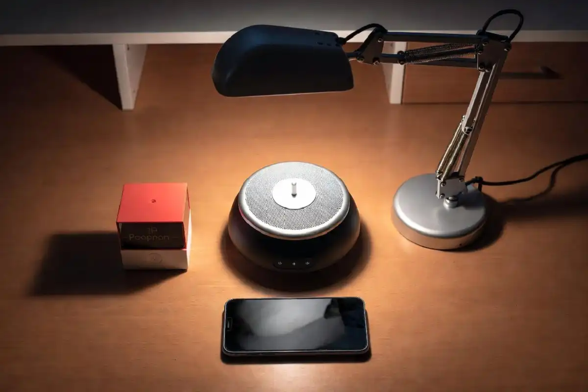 Flat lay of focus timer, lamp, sound machine, and minimalist phone on a desk
