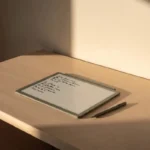 Person writing notes on a paper feel writing tablet at a clean wooden desk